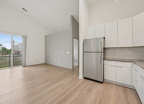 A kitchen with white cabinets and a stainless steel refrigerator.