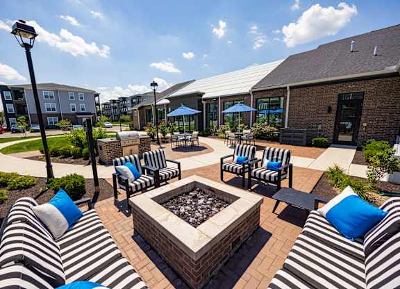 A patio with black and white striped couches and a fire pit.