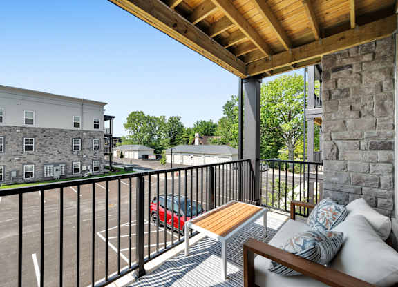 A balcony with a bench and pillows overlooks a parking lot.
