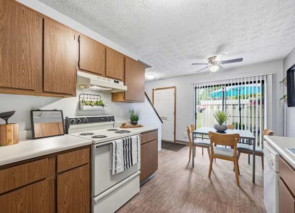 A kitchen with wooden cabinets and a white stove top oven.