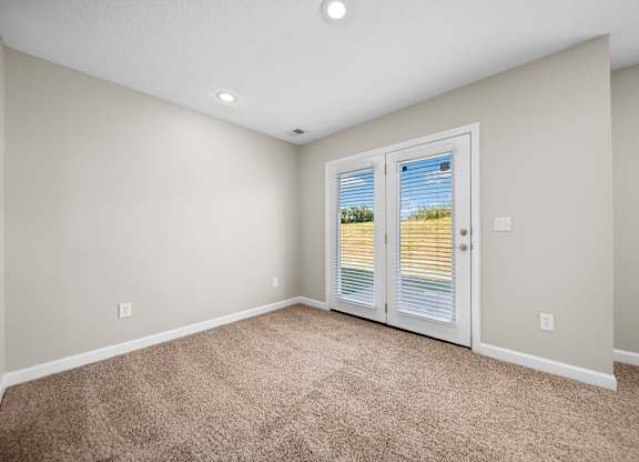 A room with a carpeted floor and a sliding door leading outside.
