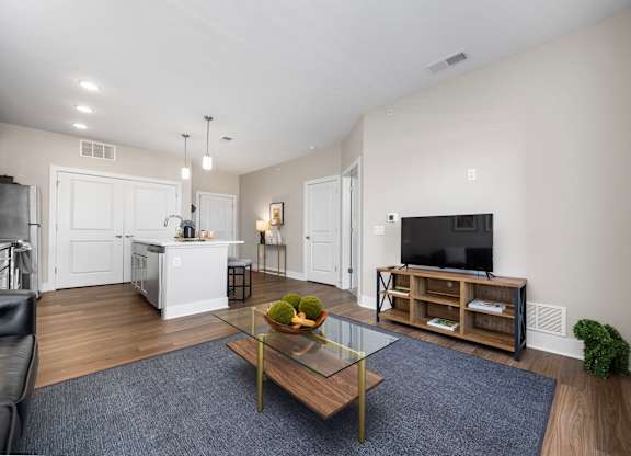A modern living room with a glass coffee table and a bowl of fruit on it.