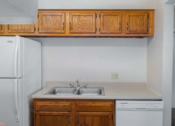 a kitchen with wooden cabinets and a sink and a refrigerator