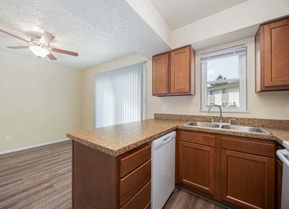 A kitchen with a white ceiling fan and wooden cabinets.