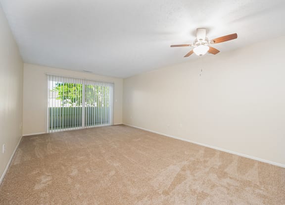 an empty living room with a ceiling fan and a window