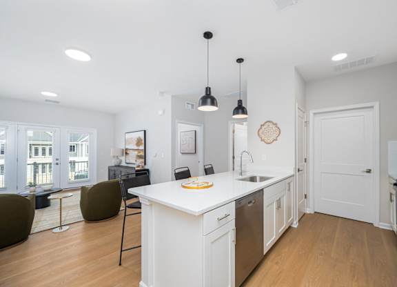 A kitchen with white cabinets and a white island with a sink.