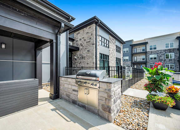 A modern house with a stone facade and a black gate.