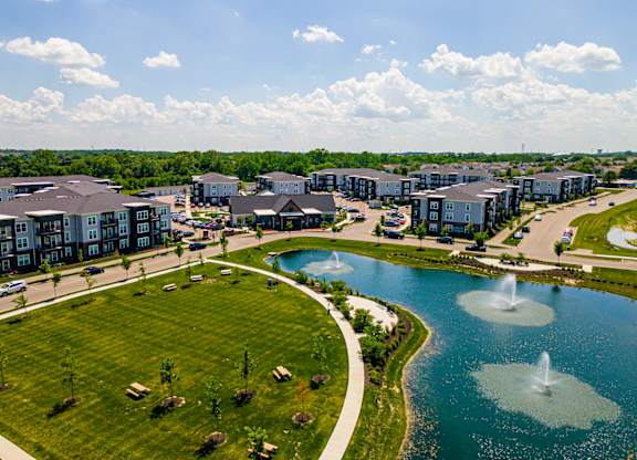 A large building complex with a fountain in the middle of a lake.