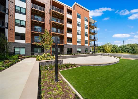 A modern apartment building with a well-maintained lawn in front.