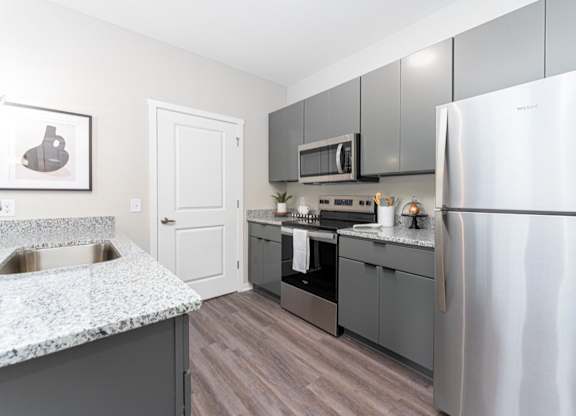 A kitchen with a stainless steel refrigerator, microwave, and oven.