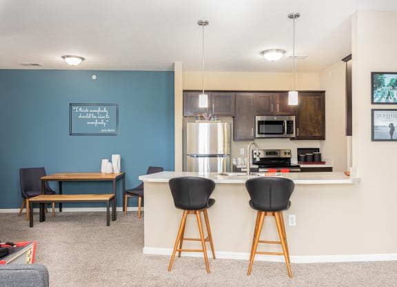 a kitchen with a bar and a living room with a table and chairs