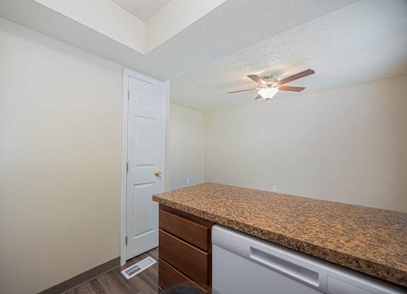 A kitchen with a counter and a fan on the ceiling.
