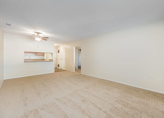 a spacious living room with carpet and a ceiling fan