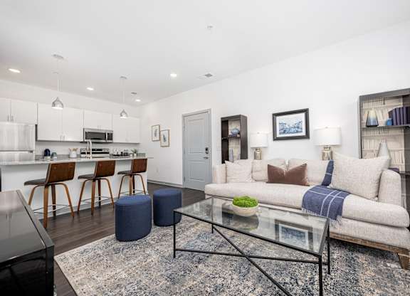 A modern living room with a glass coffee table and a grey sofa.