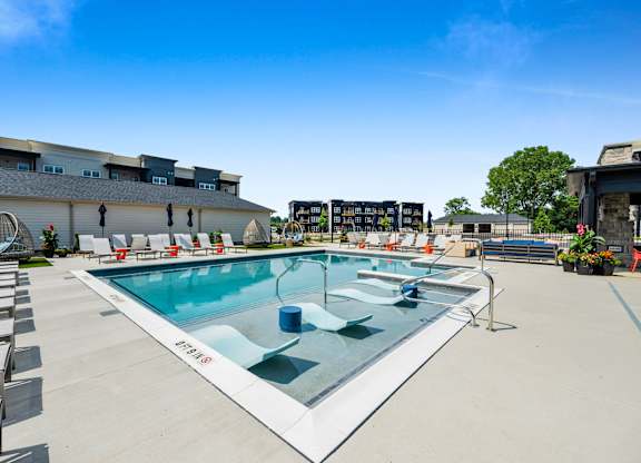 A large outdoor swimming pool with lounge chairs around it.