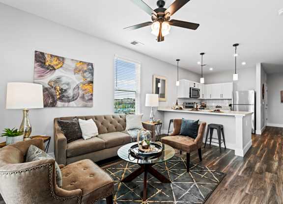 A modern living room with a grey sofa, a coffee table, and a ceiling fan.