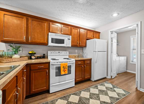 A kitchen with white appliances and wooden cabinets.