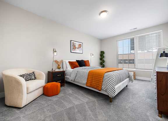 A bedroom with a bed, chair, and nightstand.