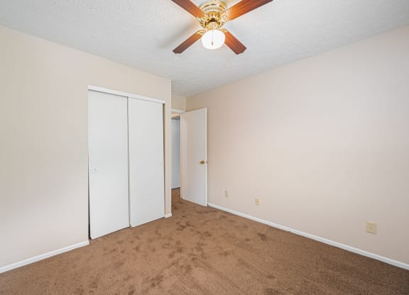 a bedroom with a ceiling fan and a closet