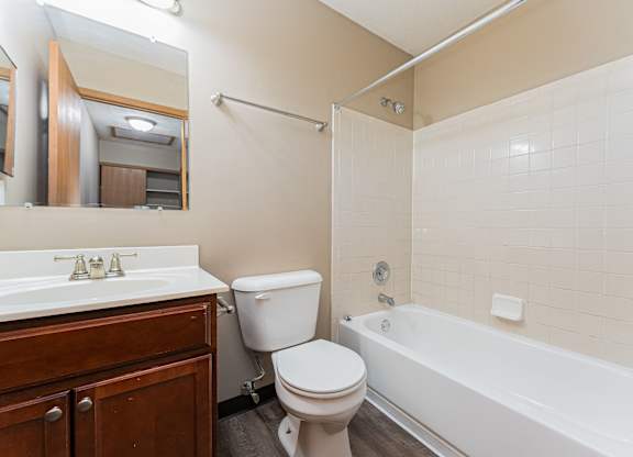 A white toilet sits next to a white bathtub in a bathroom.
