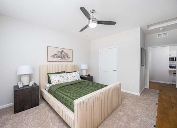 A bedroom with a bed, nightstands, and a ceiling fan.
