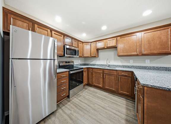 A kitchen with a stainless steel refrigerator and wooden cabinets.