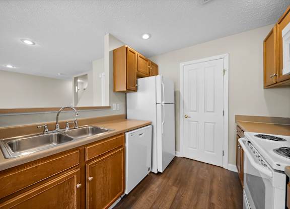 A kitchen with white appliances and wooden cabinets.