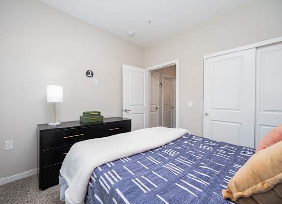 A bedroom with a bed, dresser, and two doors.