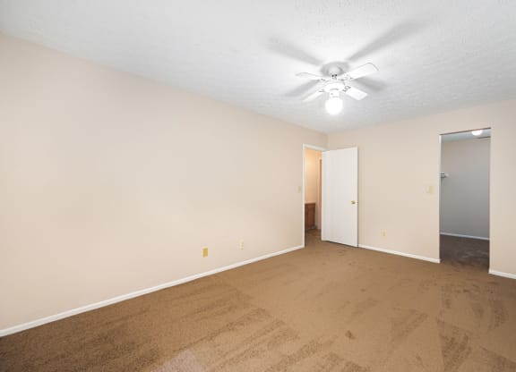 a spacious living room with carpet and a ceiling fan