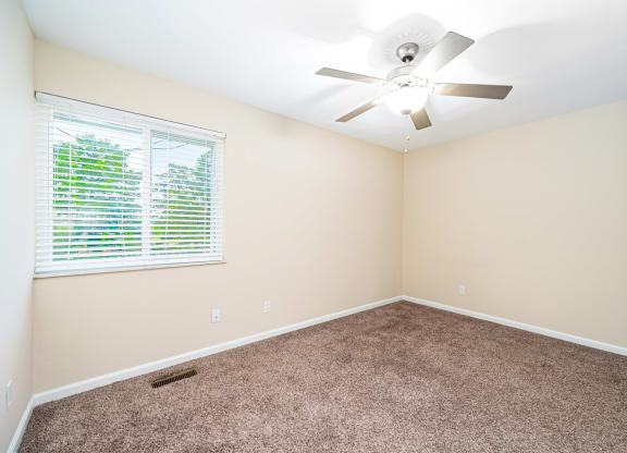 an empty room with a window and a ceiling fan