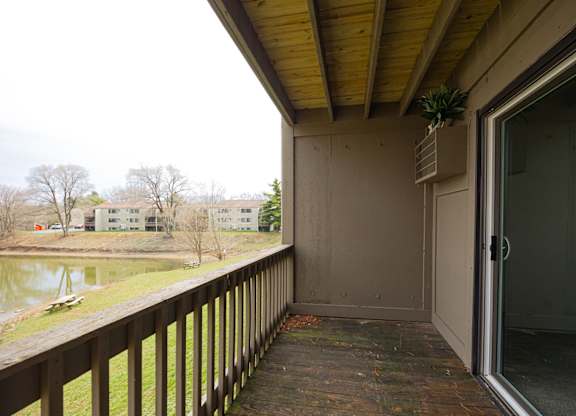 A balcony with a glass door leading to a room.