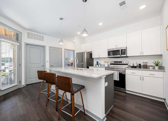 A modern kitchen with white cabinets and a wooden floor.