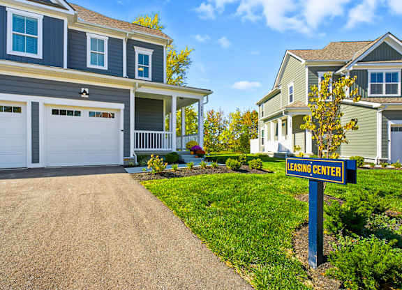 A leasing center sign is in front of a two-story house with a garage.