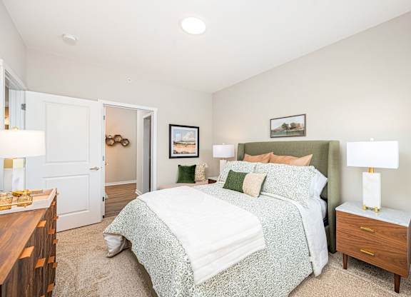 A bedroom with a bed, nightstand, and a painting on the wall.