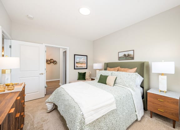 a bedroom with a bed and two lamps on top of it
