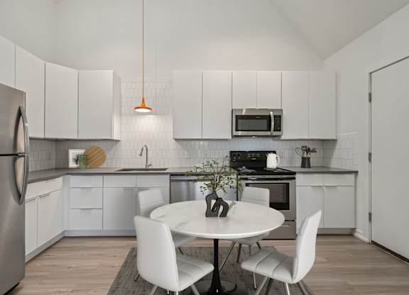 A modern kitchen with a white table and chairs.