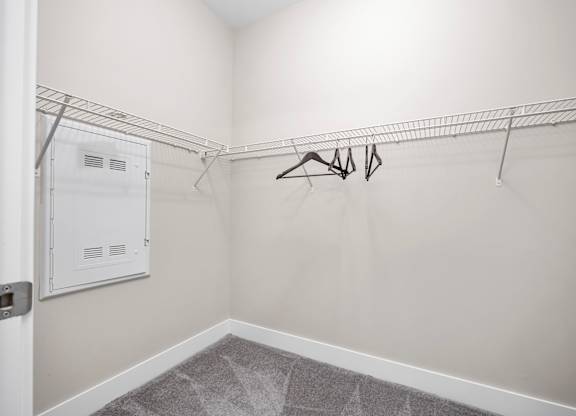 A white closet with a metal rack and a white door.