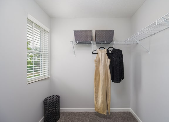 a walk in closet with a clothes rack and a window
