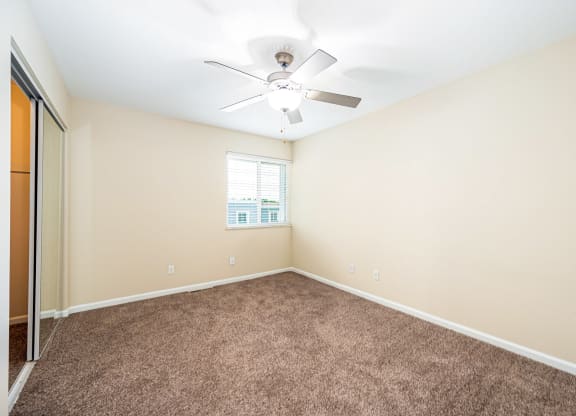 an empty room with carpet and a ceiling fan