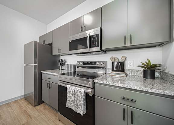 A modern kitchen with stainless steel appliances and a wooden floor.