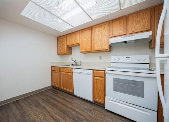 A kitchen with white appliances and wooden cabinets.