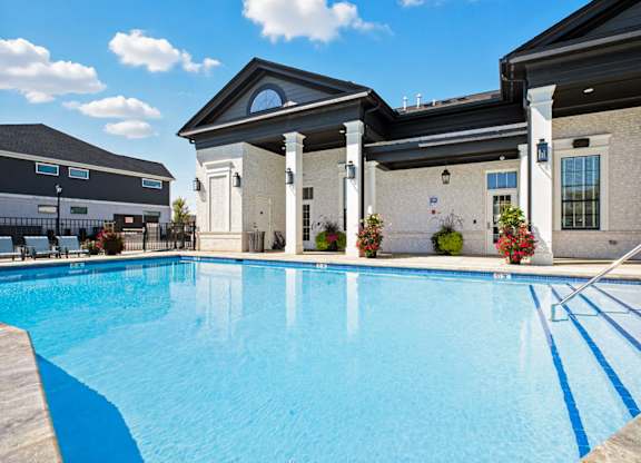 A large swimming pool in front of a building with a white pillar.