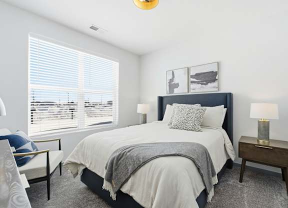 A bedroom with a large bed and a window with blinds.