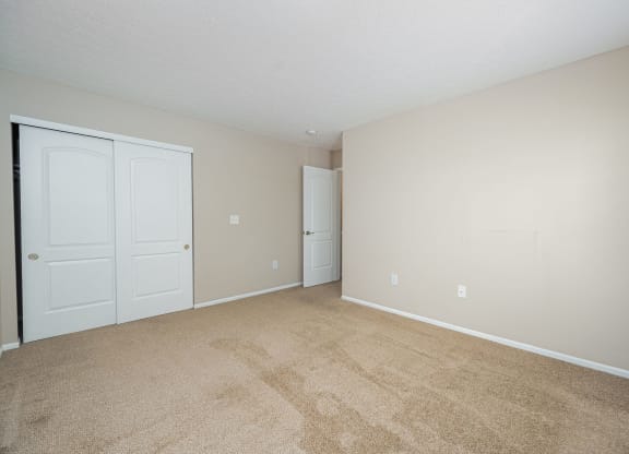 a spacious living room with carpet and white doors
