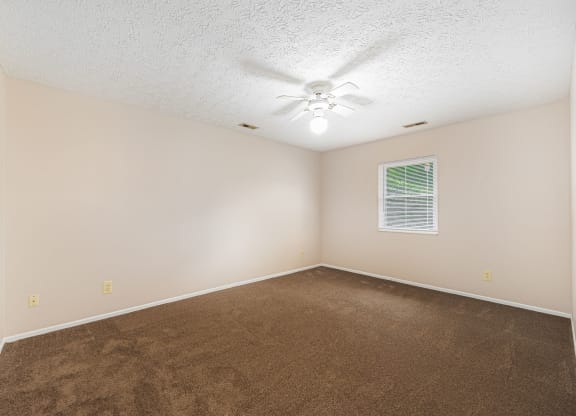 an empty living room with carpet and a ceiling fan