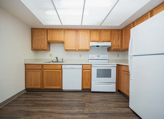 A kitchen with white appliances and wooden cabinets.