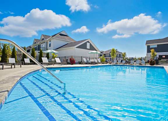 A large blue swimming pool with a diving board in the foreground.