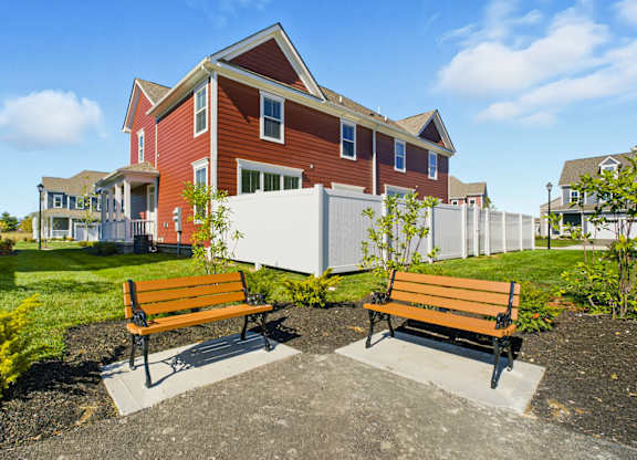 Two wooden benches are placed in front of a red building.