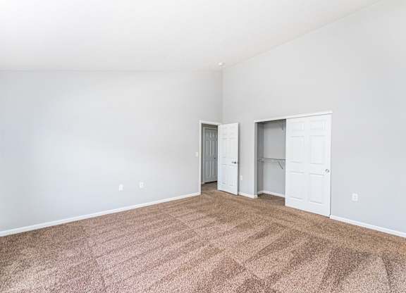 A room with carpeted floor and two white doors.