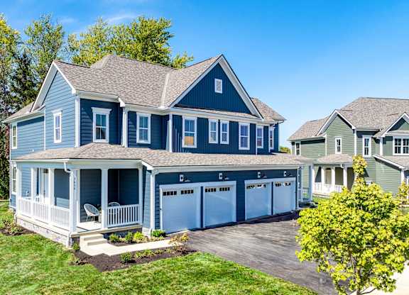 A blue house with a white porch and a garage.